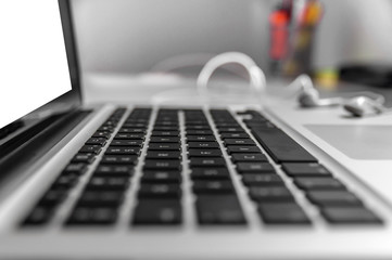 Top view of the keyboard of the laptop on white Desk with headphones