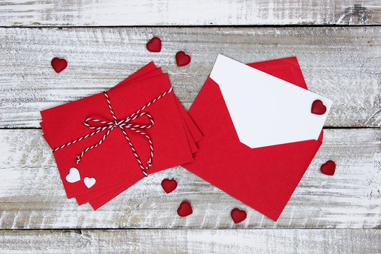 Red envelopes, note card and hearts on white wood backgroiund