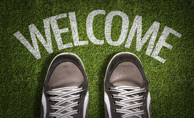 Top View of Sneakers on the grass with the text: Welcome