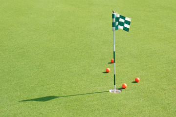 The golf hole with flag and golf balls on green grass of golf co