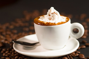 cup of coffee and coffee beans over dark background