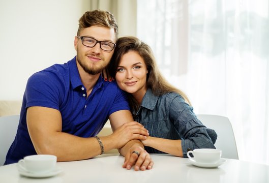 Cheerful couple behind table at home