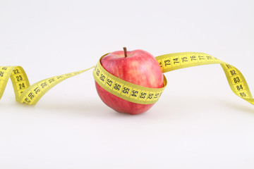 Red apple and measuring metre on a white background