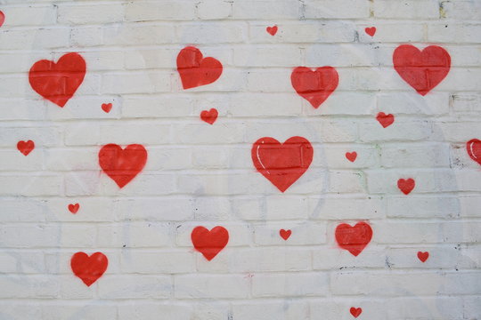 Group of red hearts painted on a white wall
