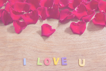 Red rose petals and colorful word "LOVE"  on a wood  background