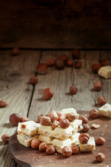 White chocolate with hazelnuts on old wooden background, selecti