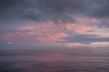 Blue hour with clouds of different colors. High clouds are orange and red, low clouds greenish blue.