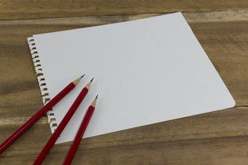 red pencil and drawing pad on wood background