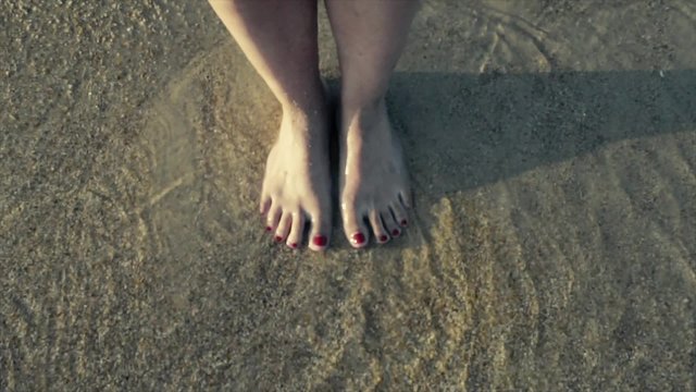 Feet on a beach and tiny waves