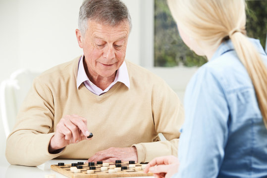 Senior Man Playing Checkers With Teenage Daughter