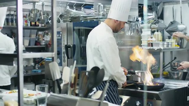  Three professional chefs in a commercial kitchen in a restaurant or hotel are preparing food. Shot on RED Cinema Camera.