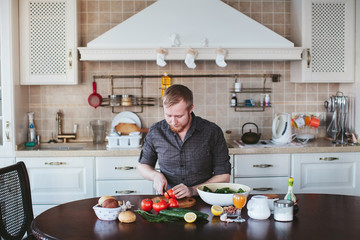 bearded man preparing vegetable salad in the kitchen