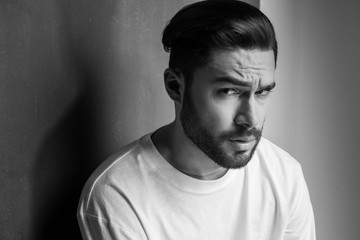 sexy man with beard looking dramatic portrait against wall