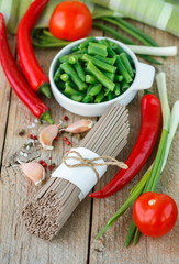 Ingredients for cooking buckwheat noodles with vegetables - dry raw buckwheat noodles, red peppers, green beans, garlic, tomatoes and spices
