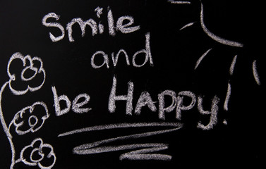Painted with chalk text on a board: smile and be happy