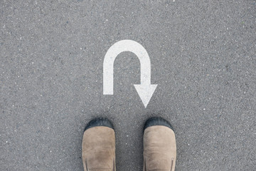 Brown suede shoes standing in front of U turn sign
