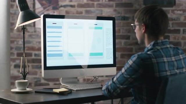 Young designer is working on a computer and developing an user interface for a mobile phone application. Shot on RED Cinema Camera.