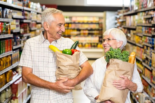 Smiling senior couple holding grocery bags