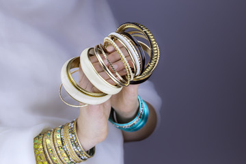 Girl hands with golden bracelets on a white cloth 