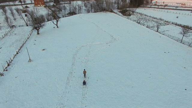 Man pulling slade with two kids, mountain village, aerial view