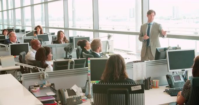 Male manager addressing workers in an open plan office