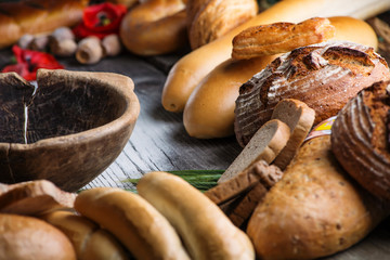rolls and breads on wooden table with wooden bowl, background for bakery or market