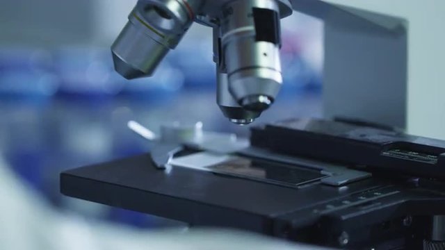 Close-up footage of a scientist setting up a microscope in a laboratory. Shot on RED Cinema Camera.