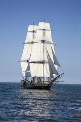 Fototapeta na wymiar A tall ship known as a brigantine sails on blue water