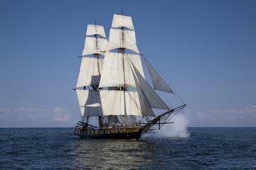 Fototapeta na wymiar Tall ship with cannons firing sailing on blue waters