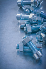 Threaded screwbolts and nuts on scratched metallic background co