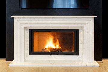 white, marble fireplace and burning fire.