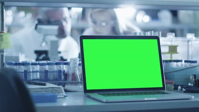 Footage of a laptop computer with green screen on a table in a laboratory. Shot on RED Cinema Camera.