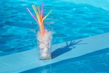 glass with ice and straws ice near the pool