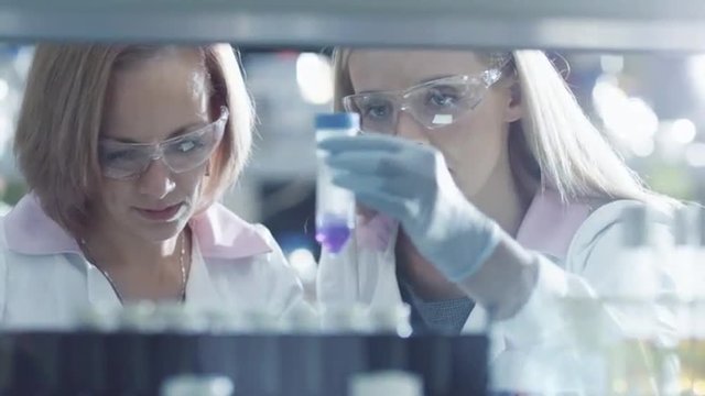 Two female scientists are working with  liquid samples in a tube in a laboratory. Shot on RED Cinema Camera.