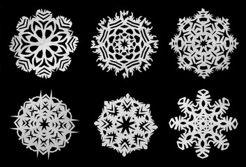 Snowflakes cut out of white paper on a black background