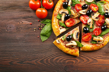 Sliced delicious tasty pizza with vegetables on wooden table
