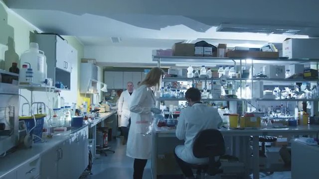 Team of caucasian scientists in white coats are working in a modern laboratory. Shot on RED Cinema Camera.