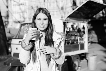 Black and white photography of beatiful young woman with a cup of hot drink outdoors 