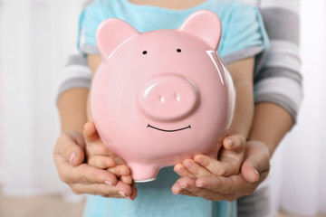 Savings concept. Hands holding piggy bank, close up