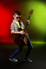 Little boy playing guitar on a bright background