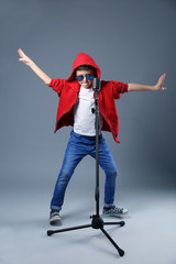 Little boy singing with microphone on a grey background