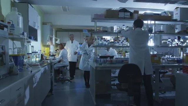 Group of caucasian scientists in white coats are working in a modern laboratory. Shot on RED Cinema Camera.