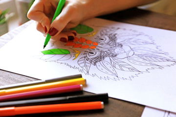 Female hand painting anti stress colouring with green felt pen