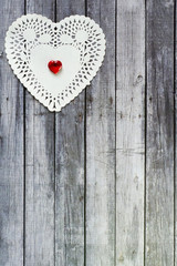 heart doily with red heart bead on top of wood table