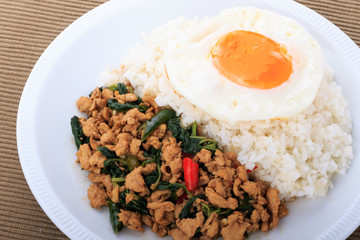 Rice topped with stir-fried chicken, basil and fried egg, fried stir basil with minced chicken on white background (Isolated Background)