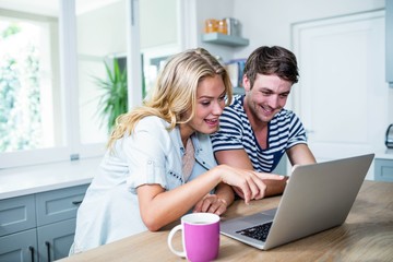 Smiling couple typing on laptop