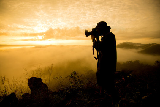silhouette man taking photo of sun rise