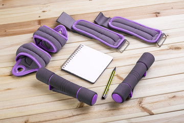 Sport Equipment. Dumbbells,  Ankle Weights, Wrist Weights And Notebook To Workout Plan On Boards. Sport Fitness Background
