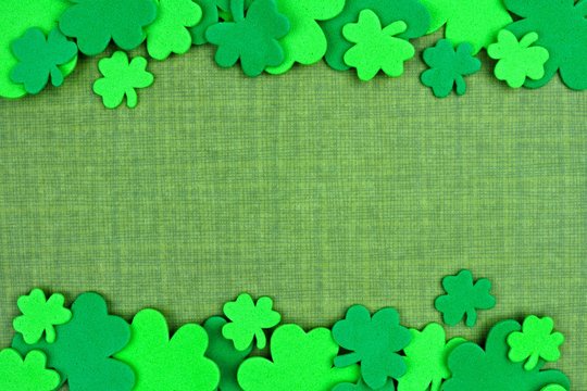 St Patricks Day double border of shamrock confetti over a green linen background