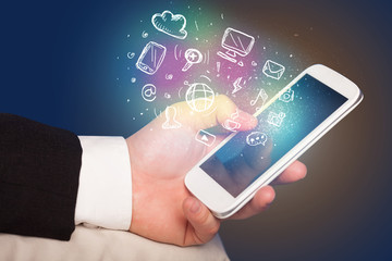 Hand holding smartphone with media icons